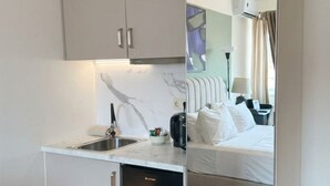 A compact hotel room with a kitchenette, a bed, and a large mirror reflecting the room. - Plaka Luminous Deluxe Suite - Located innthe heart of Athens (Athina)