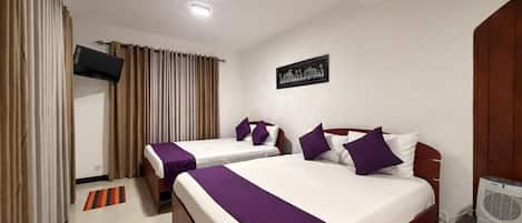A hotel room with two beds, a flat-screen TV, a wall-mounted artwork, and a ceiling light.