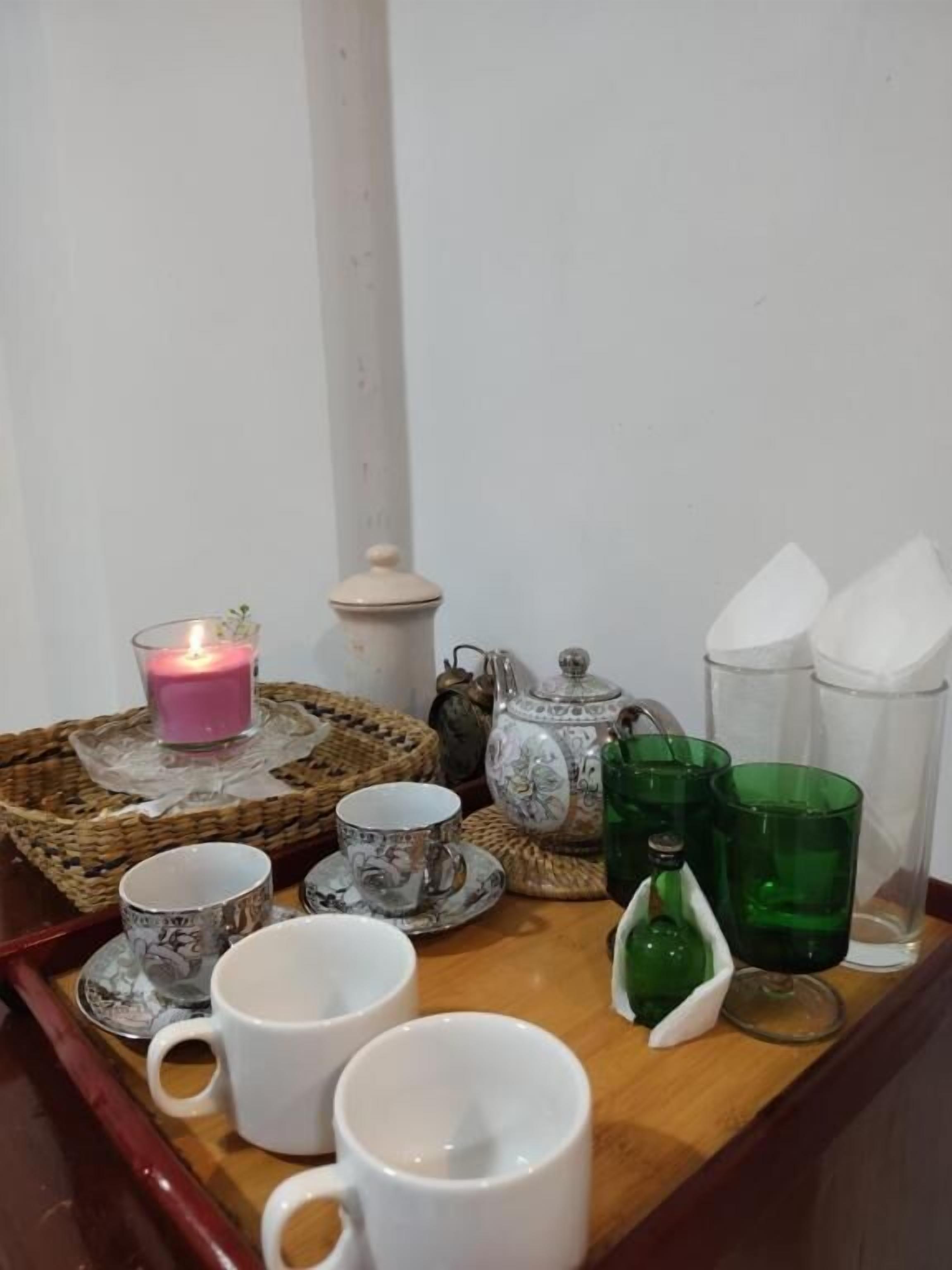 A tray with tea cups, a teapot, and a candle on a table.