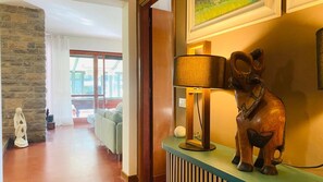 Ein Zimmer mit Steinwand, Holzboden, einer Couch, einer Lampe und einer Skulptur.