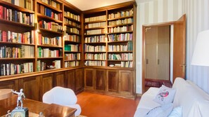 Eine Bibliothek mit Holzregalen, einem weißen Sessel und einer geschlossenen Tür.