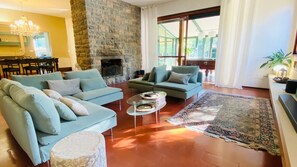 Un salon avec une cheminée en pierre, deux canapés, une table basse et un grand tapis.