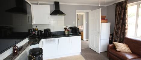 A compact kitchen with white cabinets, a black stove, and a ceiling fan.