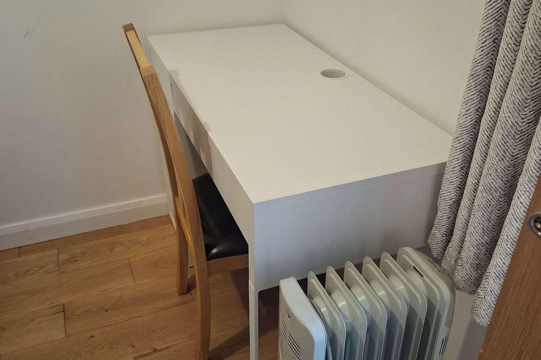 A small, white, rectangular room with a wooden chair and a radiator.