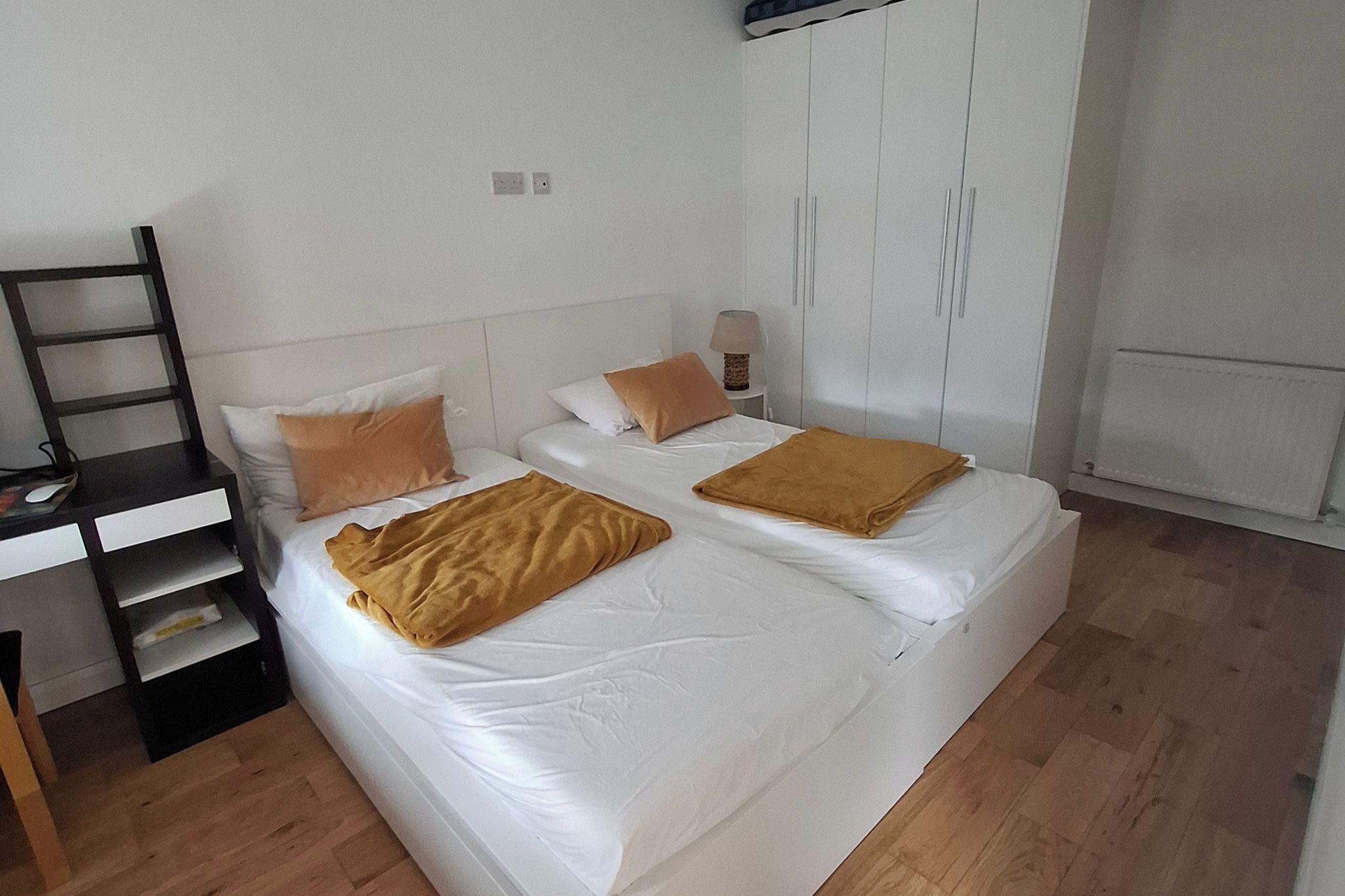 A bedroom with two beds, a wardrobe, a desk, and a chair.