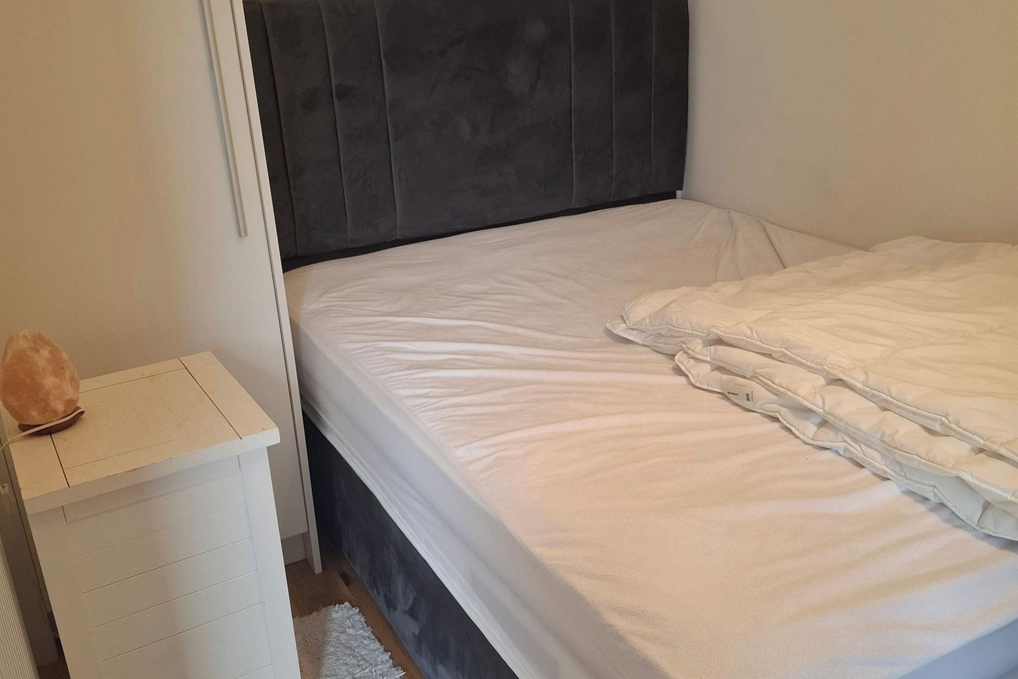 A bedroom with a bed, a bedside table, and a wall unit.