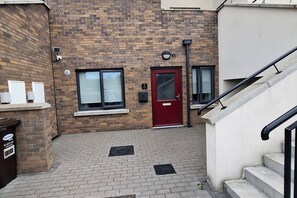 A brick building with a red door, windows, a mailbox, and a staircase. - Modern 2BDR Close to Dublin Airport and Coast (Lusk)