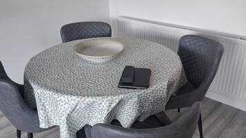 A round dining table with a polka dot tablecloth, a white bowl, and a black wallet on it.
