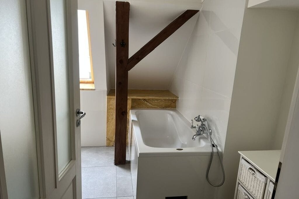 A bathroom with a bathtub, a shower, and a wooden beam structure.