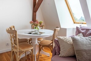 A dining area with a round table, wooden chairs, a vase with flowers, and a window with a view. - Seaside Loft Sopot - 5 min od plaży (Sopot)
