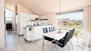 Une cuisine moderne avec des meubles blancs, un îlot central et un coin repas comprenant une table et des chaises.