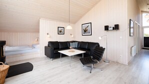 Un intérieur moderne avec un plafond en bois, un canapé en cuir noir, une table basse blanche et une chaise noire.
