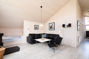 Ein modernes Interieur mit Holzbalkendecke, einer schwarzen Ledersofa, einem weißen Couchtisch und einem schwarzen Sessel.