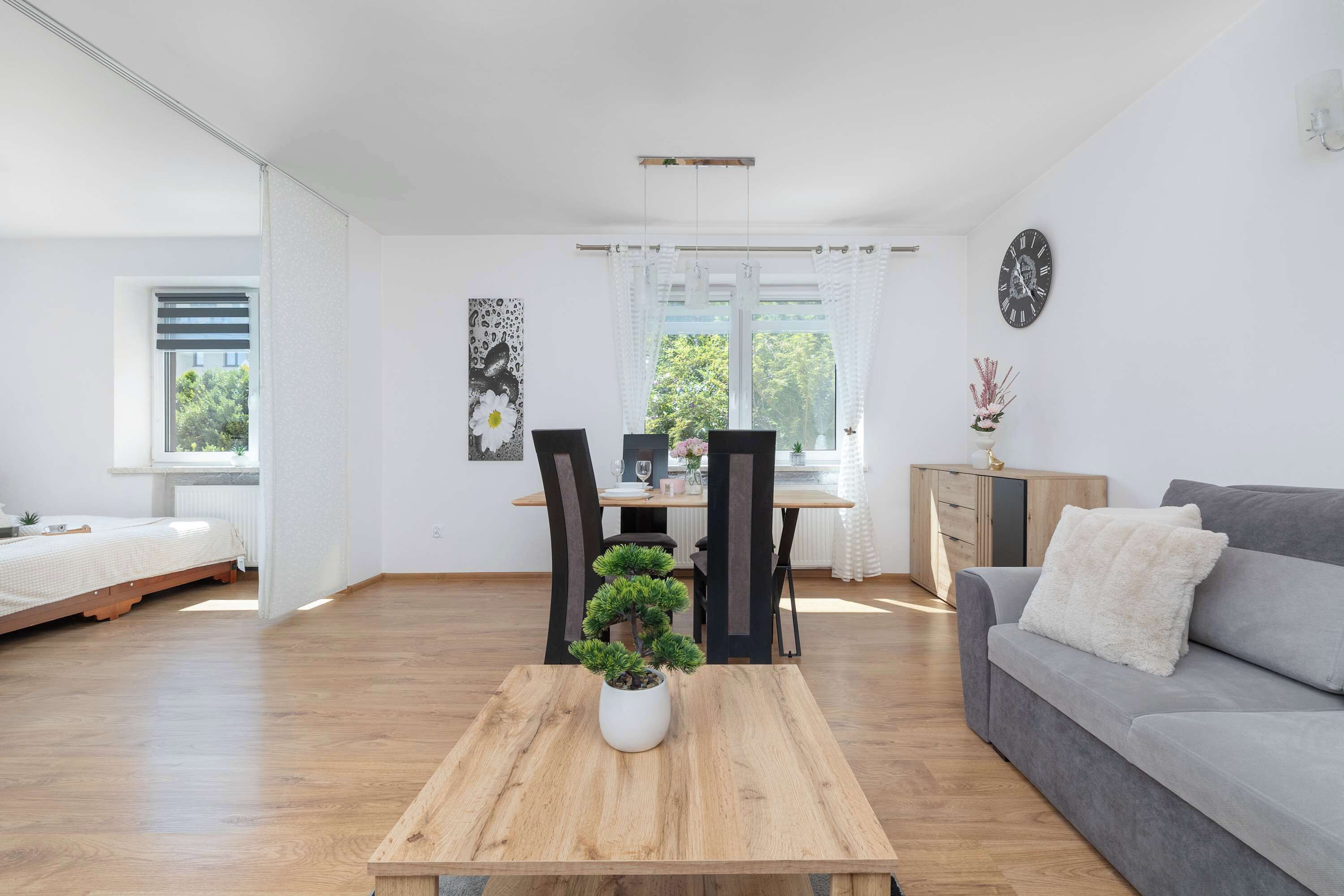 Una sala moderna con una mesa de centro de madera, un sofá gris y un comedor con mesa y sillas.
