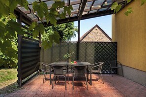 An outdoor patio with a table and chairs, a covered area with a metal roof, and a brick floor. - Spacious House with Garden | Three Bedrooms | Garage (Wieliczka)