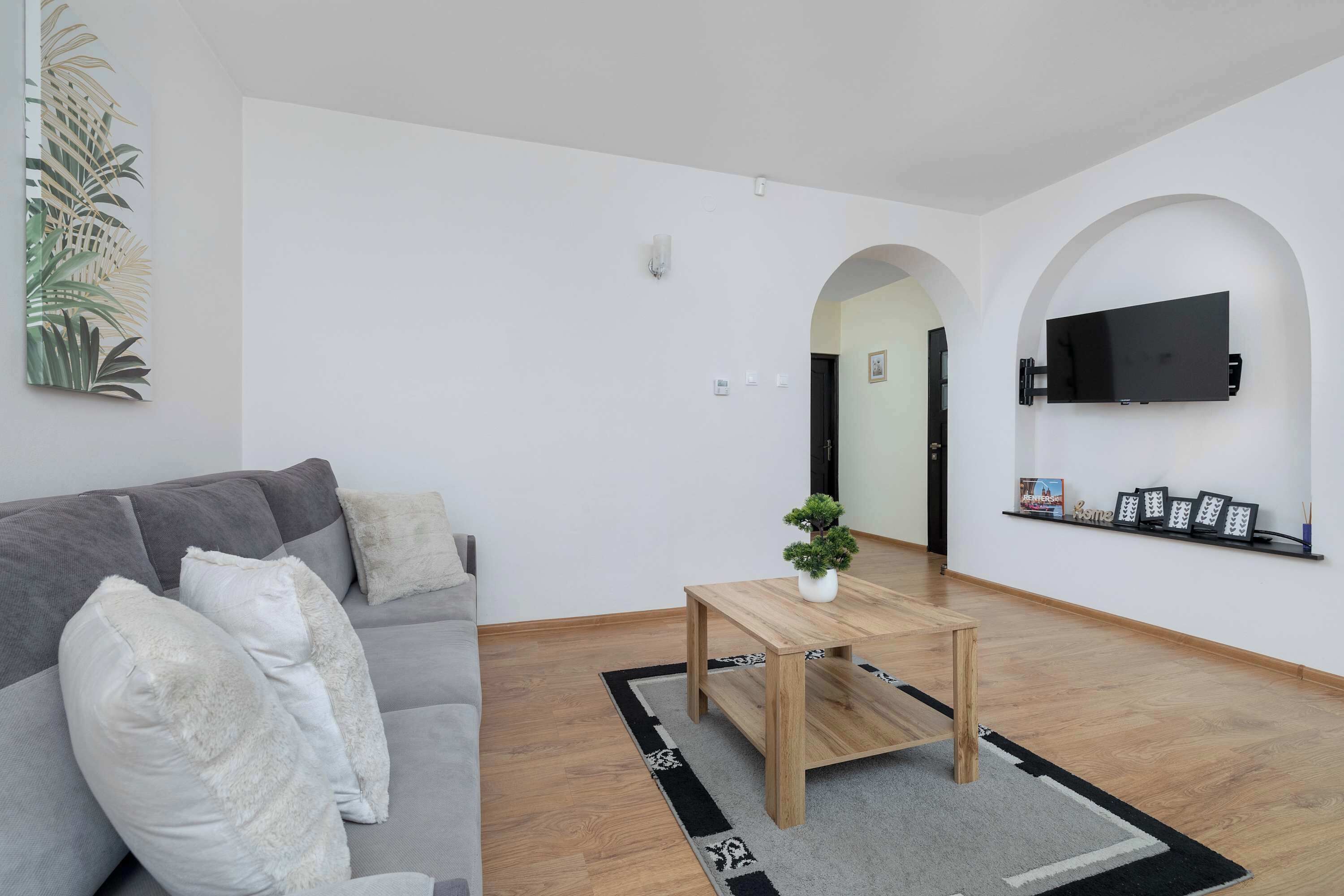 A modern living room with a grey sofa, a wooden coffee table, and a potted plant.