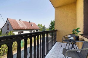 Ein Balkon mit schwarzem Geländer, einem kleinen Tisch mit Stühlen und einem Blumentopf.