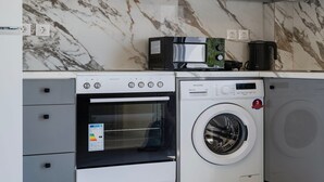 Eine kompakte Küche mit Backofen, Mikrowelle und Waschmaschine.