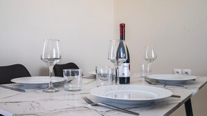Ein Esstisch, gedeckt mit Tellern, Gläsern und Besteck, mit einer Weinflasche und Gläsern darauf.
