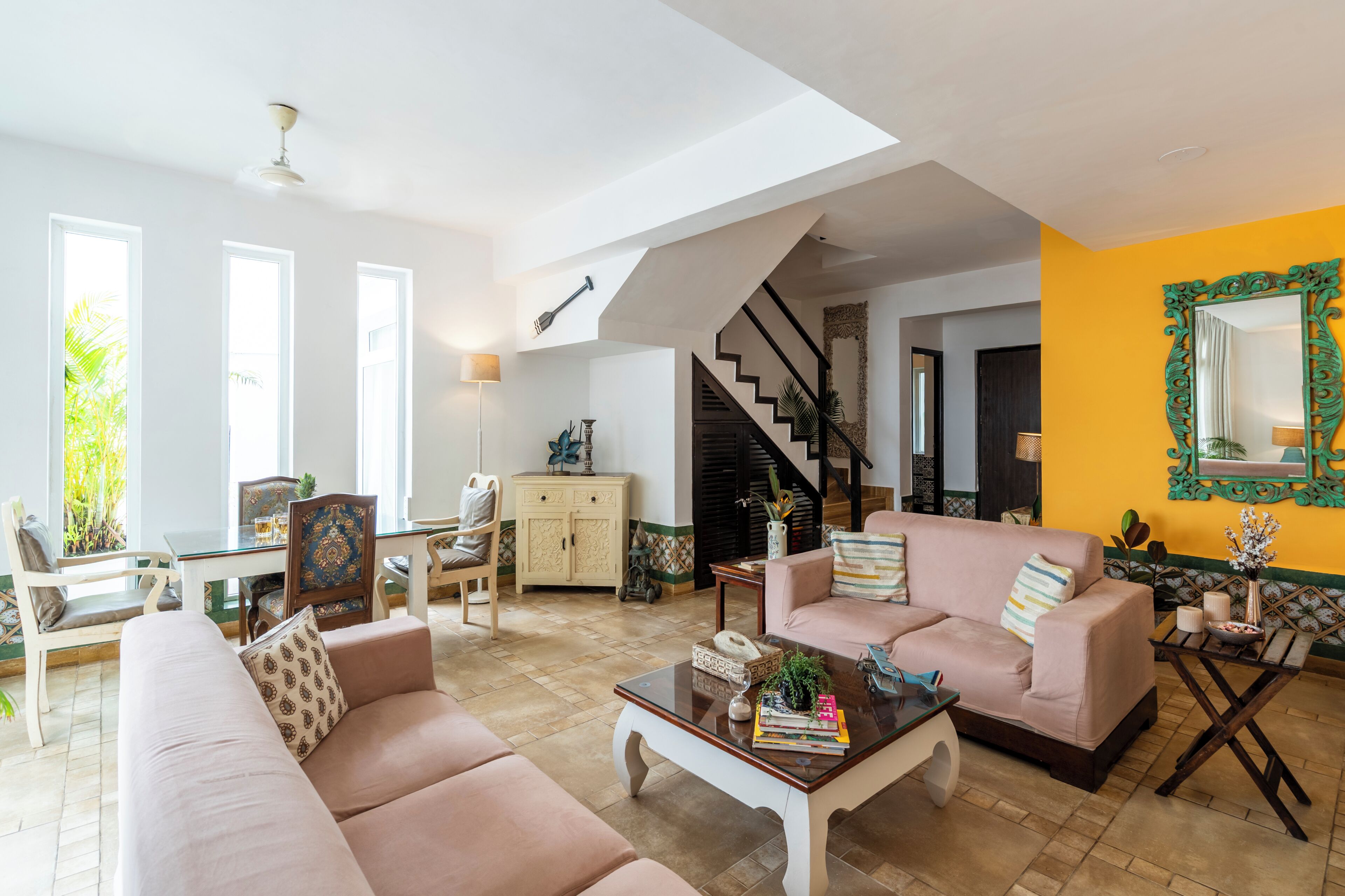 Amplia sala de estar con techo alto, una escalera y un comedor con vistas al paisaje exterior.