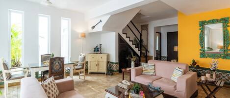 Amplia sala de estar con techo alto, una escalera y un comedor con vistas al paisaje exterior.