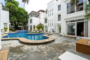A courtyard with a swimming pool, potted plants, and a building with multiple windows. - Staymaster Divli - 3BR Villa in Candolim (Candolim)