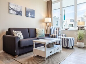 A modern living room with a sofa, armchairs, a coffee table, and artwork on the wall. - Gemutliche Ostsee-oase, 4 Gaste (Lübeck)