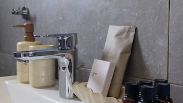 A bathroom with a white sink, a soap dispenser, a shower cap, and a bag of toiletries.