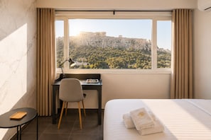 A hotel room with a bed, a desk, a chair, a lamp, and a view of a historic building. - Athens Majesty Supreme Suite - Located in the heart of Athens (Athina)