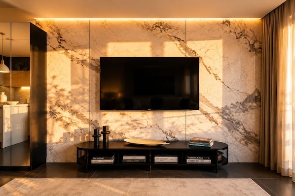 Ein modernes Wohnzimmer mit großem Flachbildfernseher an einer Marmorwand, einer schwarzen Unterhaltungsanlage mit Büchern und einem minimalistischen Design.