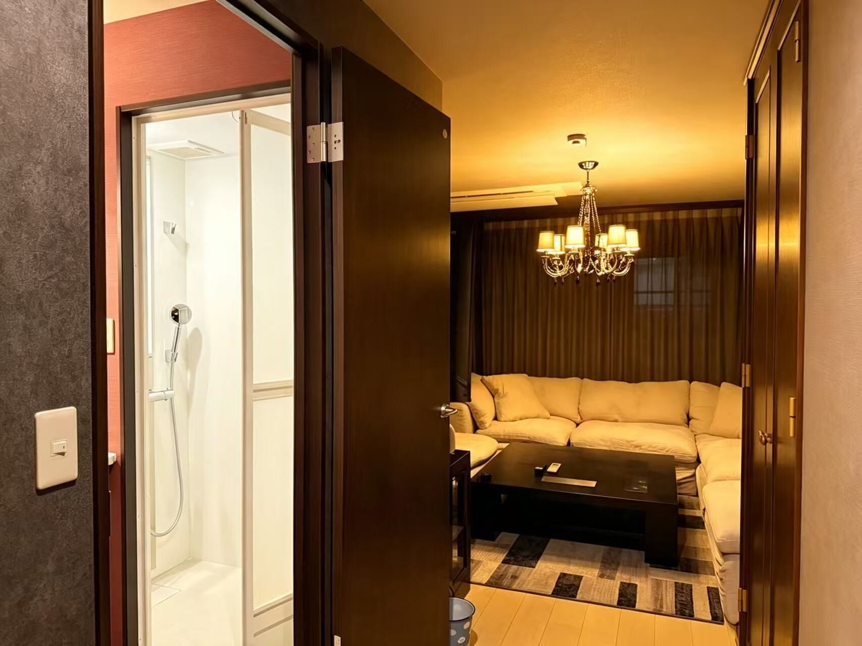 A hotel room with a shower, a sofa, a coffee table, and a chandelier.