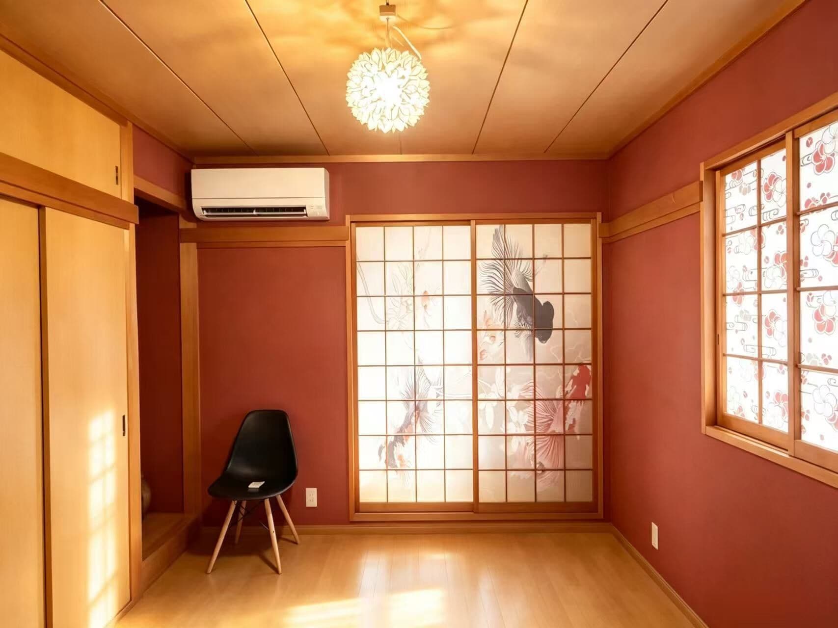 A room with a sliding shoji screen, a black chair, and a ceiling light fixture.