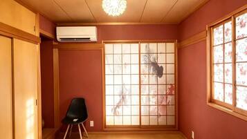 A room with a sliding shoji screen, a black chair, and a ceiling light fixture.