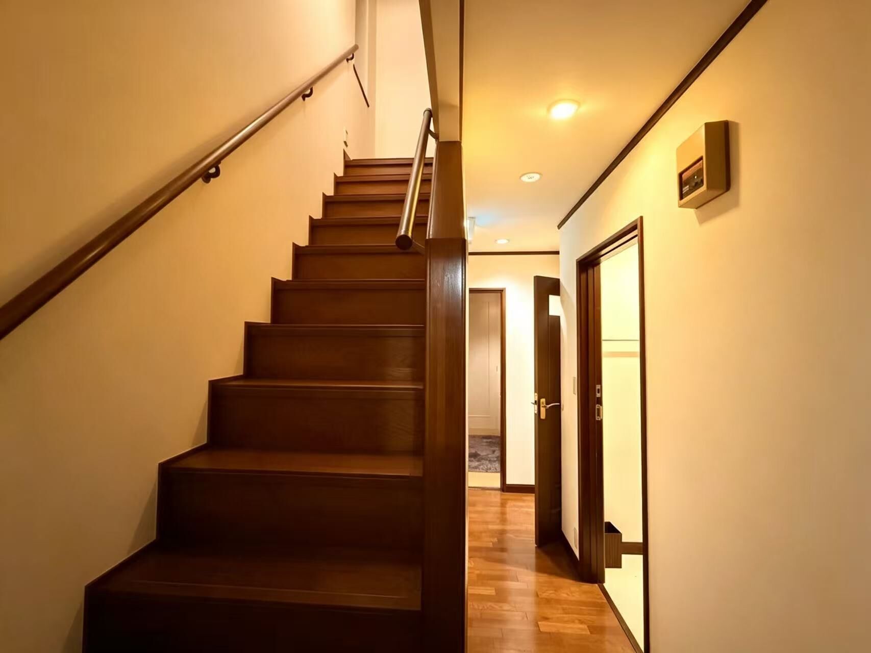 Una escalera de madera con barandilla que lleva a una puerta arriba.