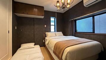 A bedroom with a bed, a window, a chandelier, and an air conditioning unit.