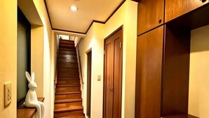 A hallway with wooden flooring, a white rabbit decoration, and wooden cabinets. - PIKA STAY Shimada House (Tokyo)