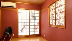 A room with a sliding shoji screen, a black chair, and an air conditioning unit. - PIKA STAY Shimada House (Tokyo)