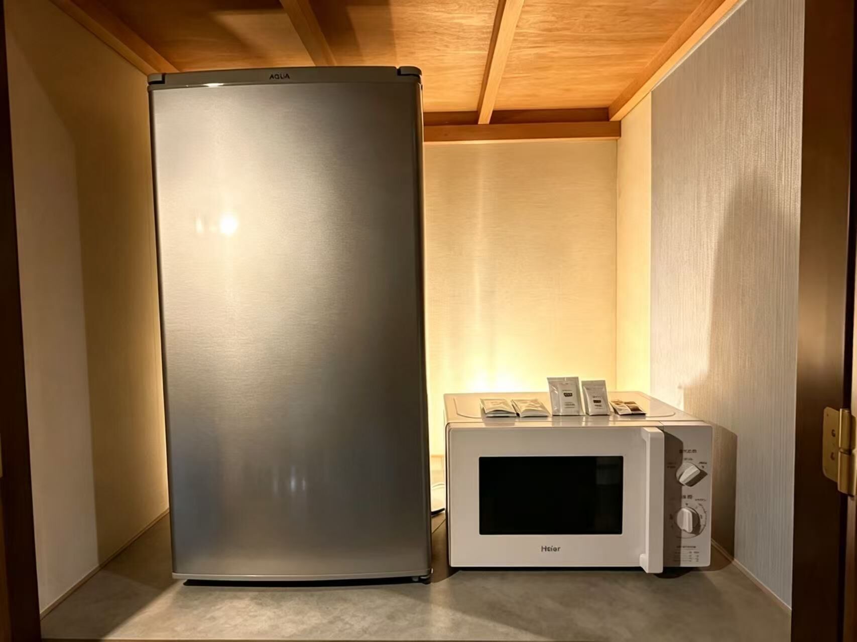 A compact kitchen area with a stainless steel refrigerator and a white microwave oven.