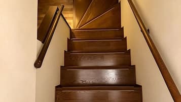 A wooden staircase with a handrail on the right and a wooden wall on the left.