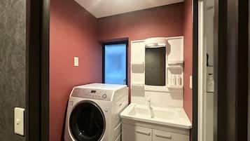 A compact laundry room with a washing machine, a sink, and a mirror.