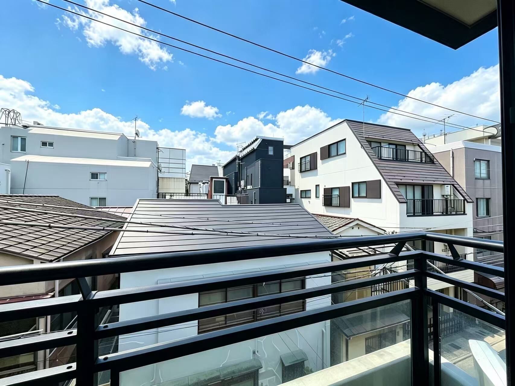 A residential building with multiple floors, balconies, and a clear sky.