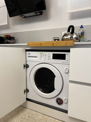 A compact, modern washing machine with a digital display, a control panel, and a 10-year warranty sticker. - Ea casa de mì2 – The Enchantment of Living Venice (Venezia)
