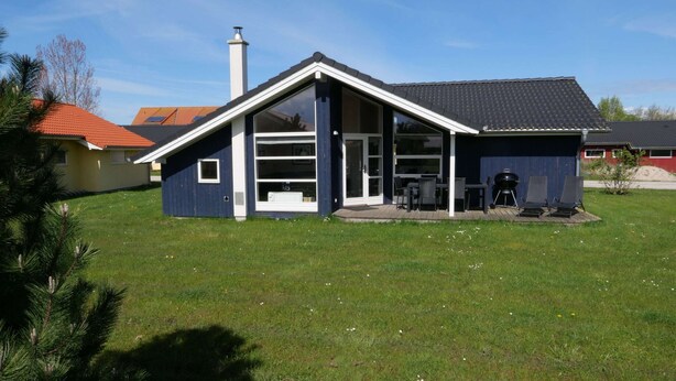 A modern single-story house with a large glass door entrance, a covered patio area, and a chimney. - Grobenbrode - Luftiger Kustenurlaub (Grossenbrode)