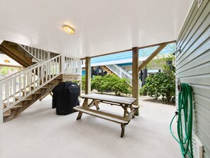 A covered outdoor area with a wooden bench, a barbecue grill, and a staircase leading to an upper level. - Lady Luck - Second Row in Surfside Beach (Surfside Beach)