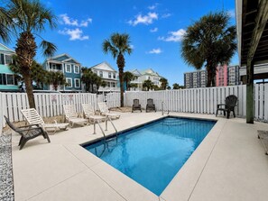 A rectangular swimming pool with a white deck, surrounded by lounge chairs and palm trees. - Lady Luck - Second Row in Surfside Beach (Surfside Beach)