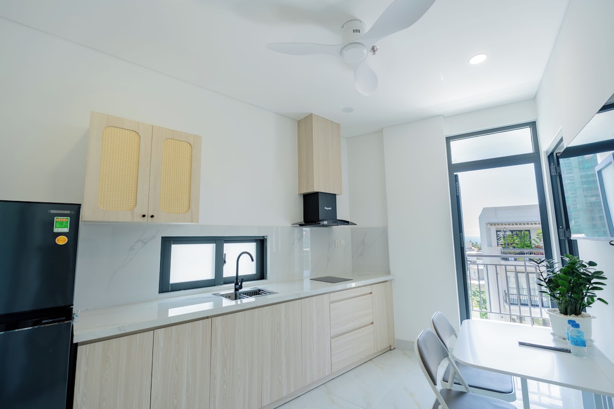 Una cocina moderna con refrigerador integrado, un lavamanos y una ventana con vista a la ciudad.