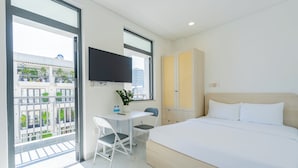 Habitación de hotel con cama, escritorio con silla, televisor y vista al balcón.