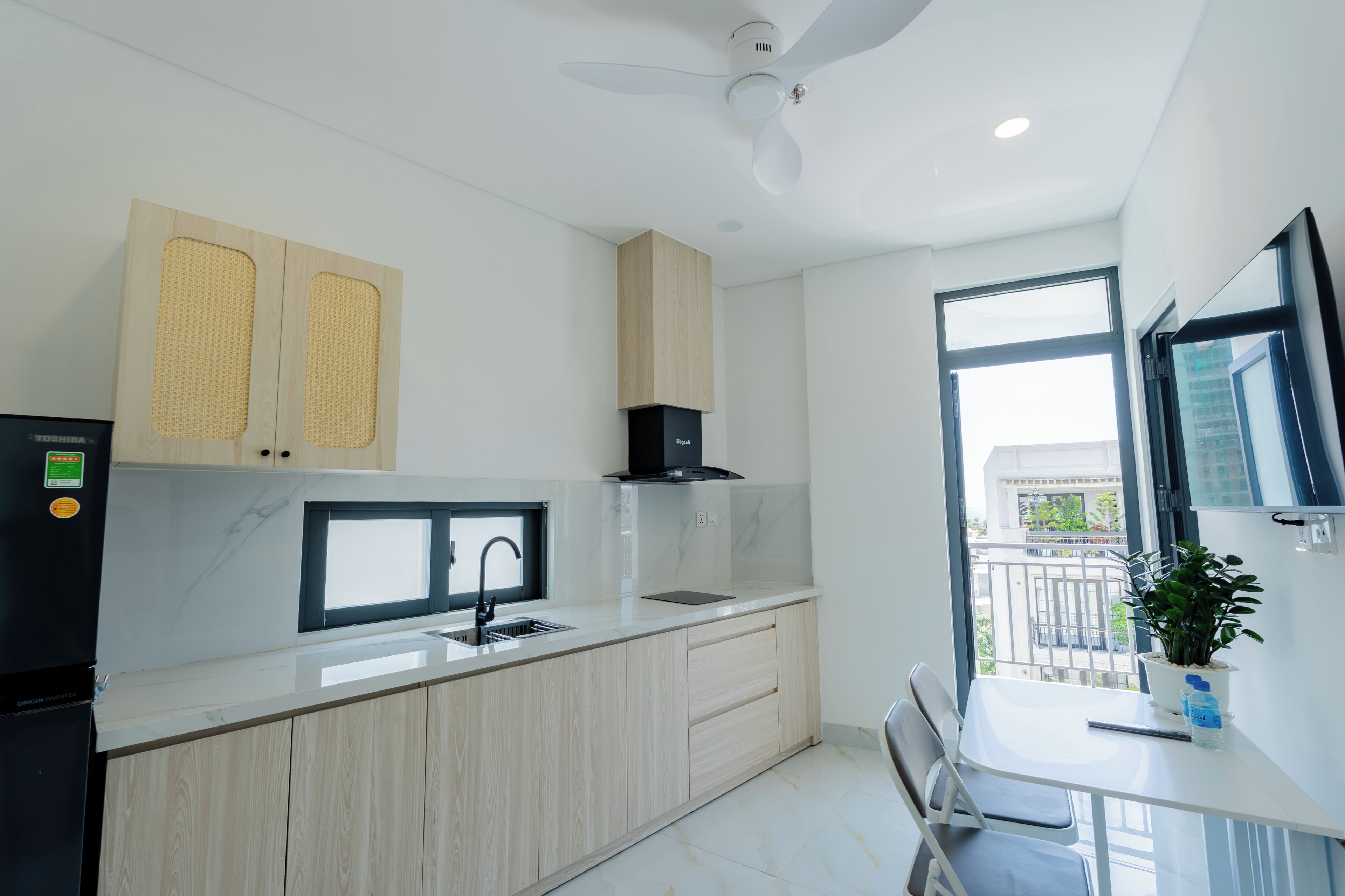 A modern kitchen with a built-in stove, a sink, and a window overlooking a cityscape.