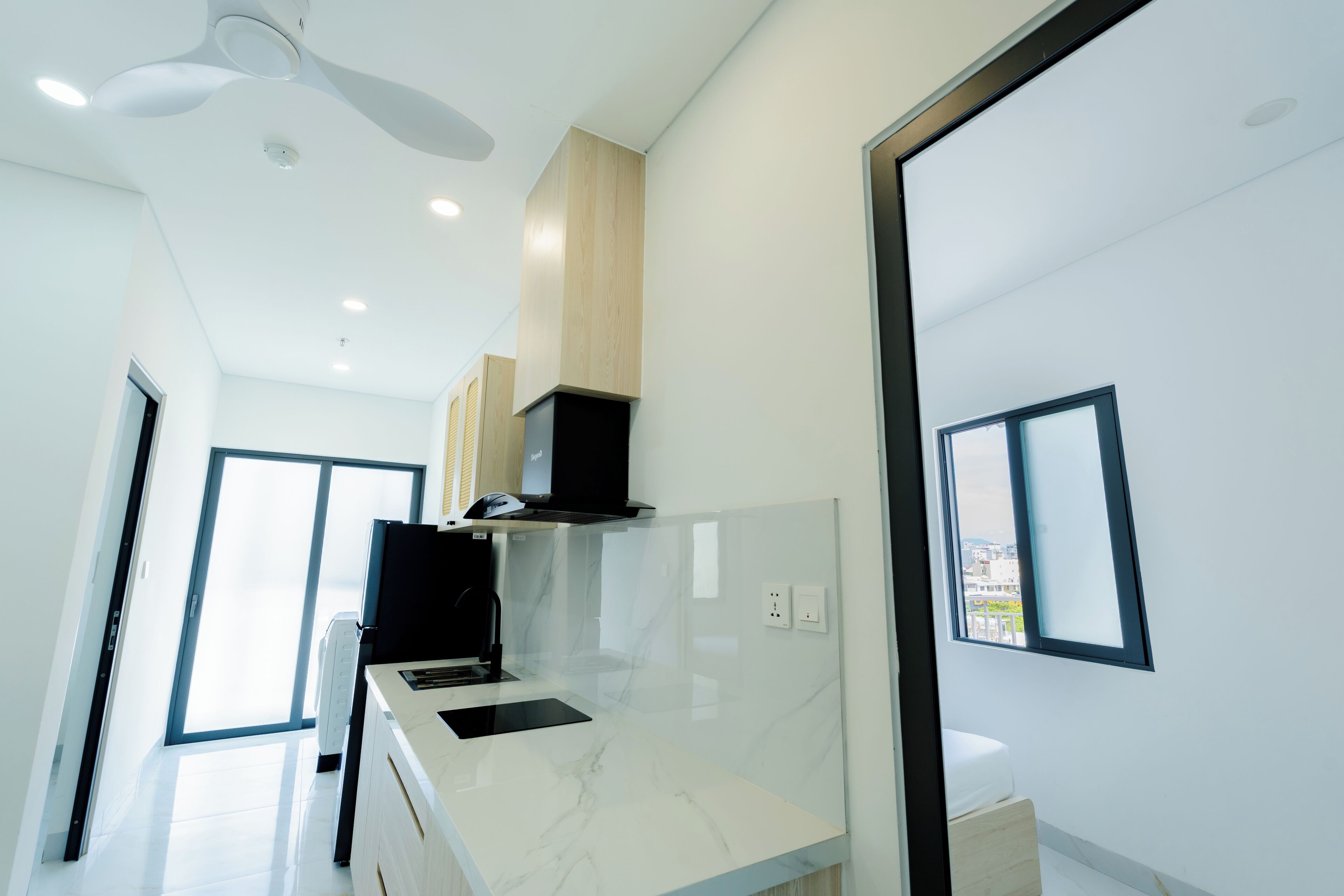 A modern kitchen with a marble countertop, built-in cabinets, and a ceiling fan.