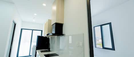 A modern kitchen with a marble countertop, built-in cabinets, and a ceiling fan.
